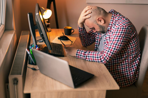 Ein verzweifelter Mann vor dem Laptop nach einer Immobilienbewertung durch eine Online-Immobilienbewertung